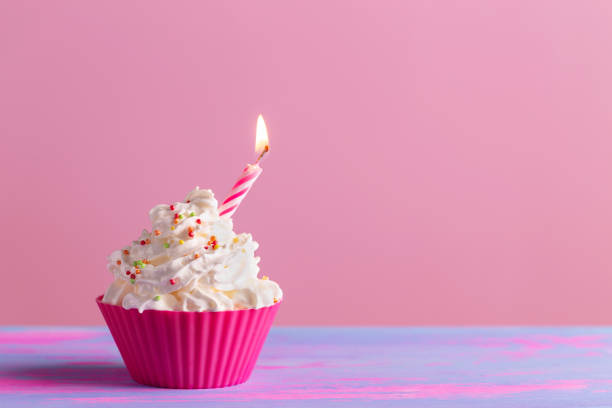 istock Birthday cake cupcake with candle, sparkler on pink background 1317766866
