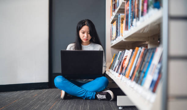 istock University student on laptop sitting in library. 1317769870