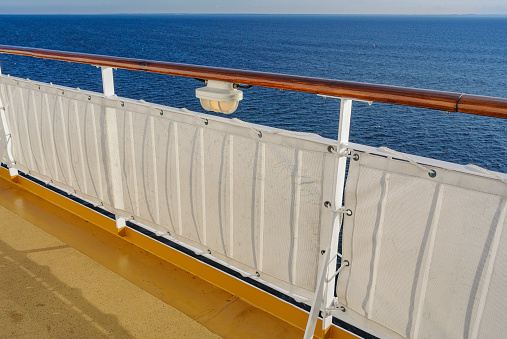 Close up of white cruise ship railing or safety railing in the front of a cruise ship. Sea view with blue sky and white clouds. Vacation in the Seychelles.