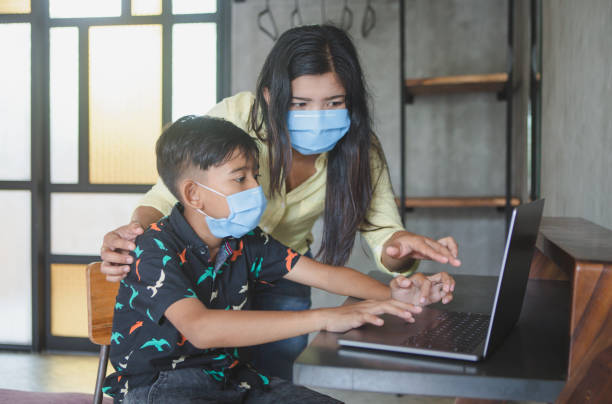 istock Lockdown and school closures. Mother helping her child with face mask studying online classes at home. Quarantine, self-isolation, online education concept, home schooler during COVID-19 pandemic 1317770771