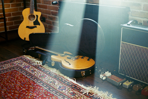 A beautiful grayscale shot of an acoustic guitar leaned on a wooden door on a wooden surface