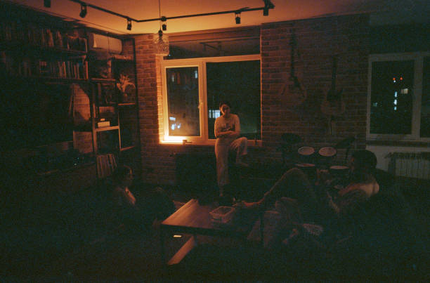 Two women and man  having fun at home. Playing guitar, talking
