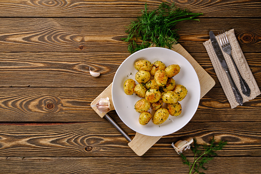 Delicious and useful food. Pierced young potatoes in the oven with spicy herbs and garlic on the old rustic table