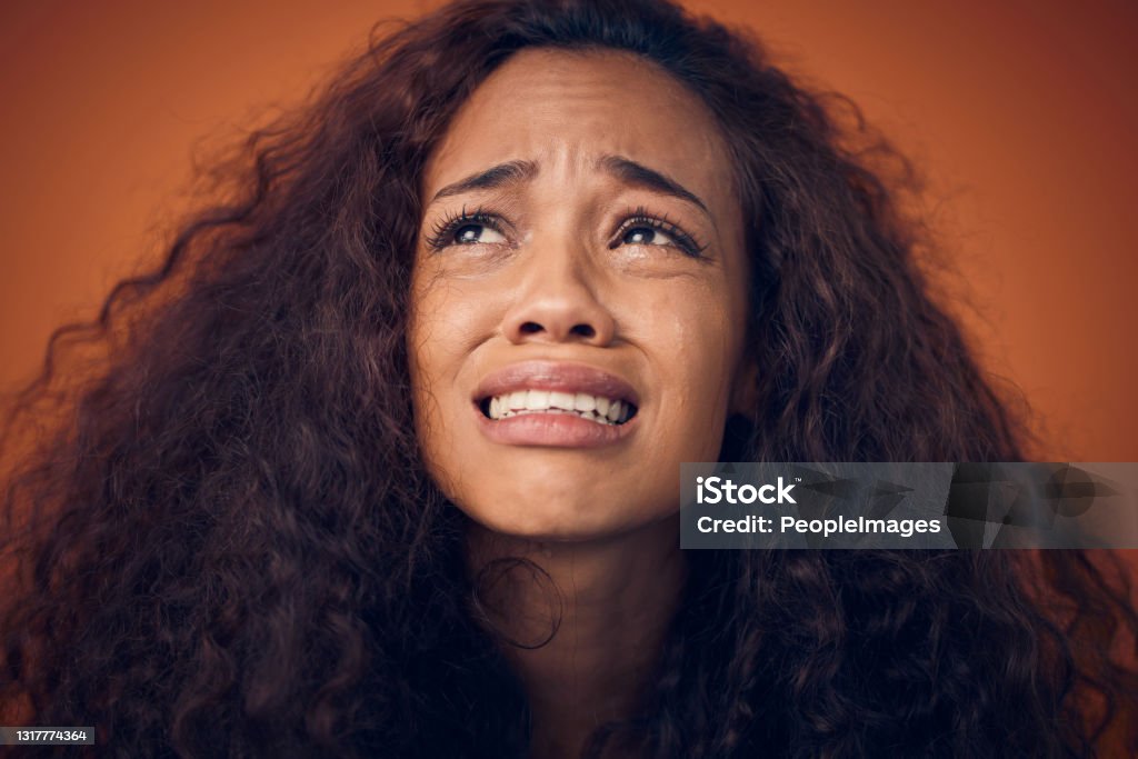Shot of a woman with curly brown hair crying against an orange background These hair products and their empty promises Sadness Stock Photo