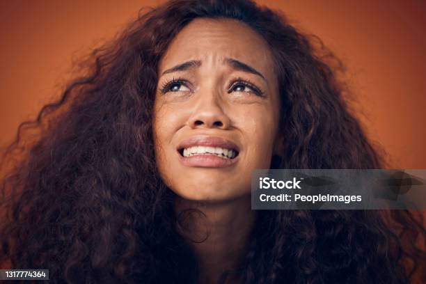 Shot Of A Woman With Curly Brown Hair Crying Against An Orange Background Stock Photo - Download Image Now