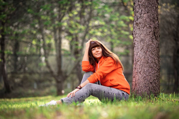 istock A beautiful girl is sitting in the grass by a tree and posing. 1317776984