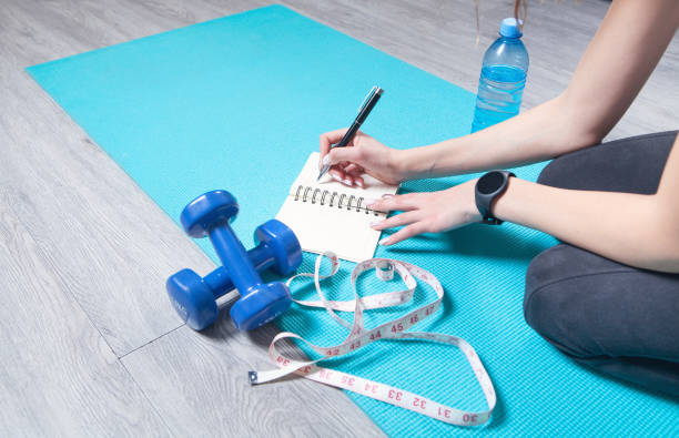 istock Young woman sitting in mat writes training plans at home. 1317779459