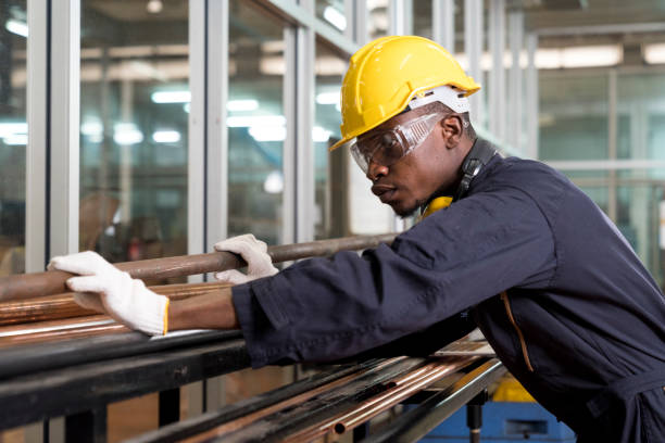 A worker at the factory. New steel pipes. Engineer is holding in hands a pipe tool. Tube tool. stock photo