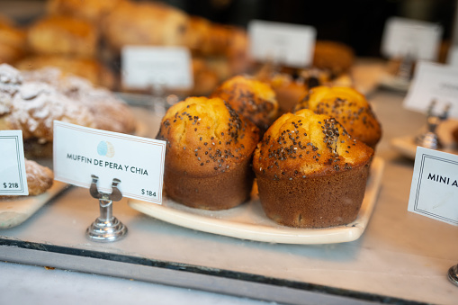 Close-up shot of fresh muffins displayed in food shelf at bakery. Muffin de pera chia in coffee shop.