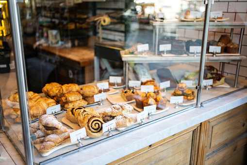 View of various baked food in glass cabinet at bakery. Fresh snacks displayed for sale in a coffee shop.