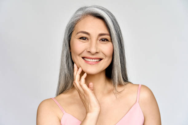 Senior happy middle aged mature asian woman portrait. Skin care advertising. Headshot portrait of gorgeous happy middle aged mature asian woman, senior older 50 year lady looking at camera touching her face isolated on white. Ads of lifting anti wrinkle skin care, spa. 1814 stock pictures, royalty-free photos & images