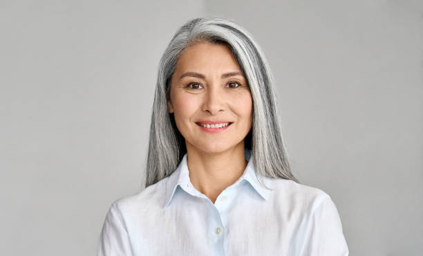 headshot of senior 50 years old asian businesswoman on grey background. - women middle aging process 45 50 years imagens e fotografias de stock
