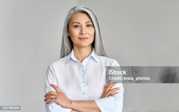 Headshot Of Mature 50 Years Old Asian Business Woman On Grey Background Stock Photo - Download Image Now