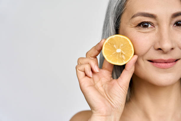 closeup portrait of mid aged beautiful asian woman holding juicy lemon. - vitamin a letter a food orange imagens e fotografias de stock