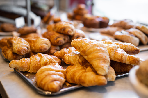 Close-up of croissants displayed in a bakery. View of fresh snacks displayed for sale in a coffee shop.