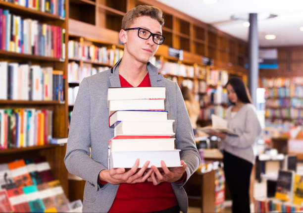 istock Tired student standing with pile of books 1317788140