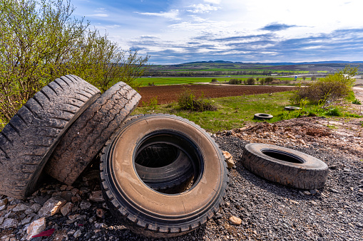 Dumped used truck tires near dirt road and agricultural field, pollution and recycle concept. Illegal landfill near Sofia, Bulgaria. The photo is shot with Sony A7III camera