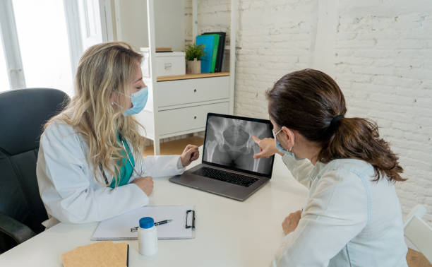 Female doctor and woman patient in face masks talking in hospital o clinic office. Explaining gynecology test results. Women Health Care, Brest or Ovarian Cancer Prevention, Diagnosis and Treatment. stock photo