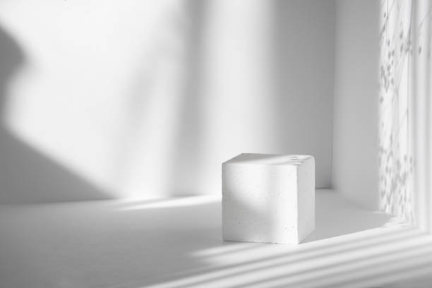 istock White cube against background of clean walls in sunlight. Hard shadows from sun's rays, in form of stripes of different widths. 3d podium concept for packaging and cosmetics presentations 1317792035