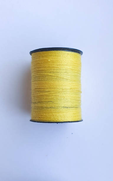 istock Beige thread with wooden bobbin on white background 1317792551