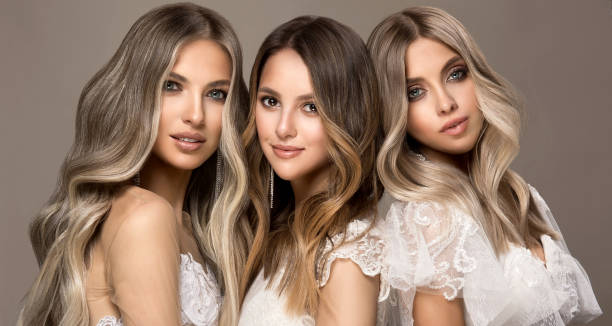 Three young attractive models  is demonstrating professionally dyed long hair. Elegance, hairstyling and makeup. Three young attractive models dressed in wedding gowns is demonstrating professionally dyed long hair. Multilayer, complex colouring of woman hair. Modern trends of hair dye. Hairstyling art. hair length stock pictures, royalty-free photos & images