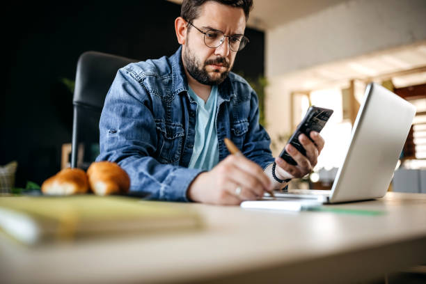 istock Cheerful man using smart phone at home office 1317794848