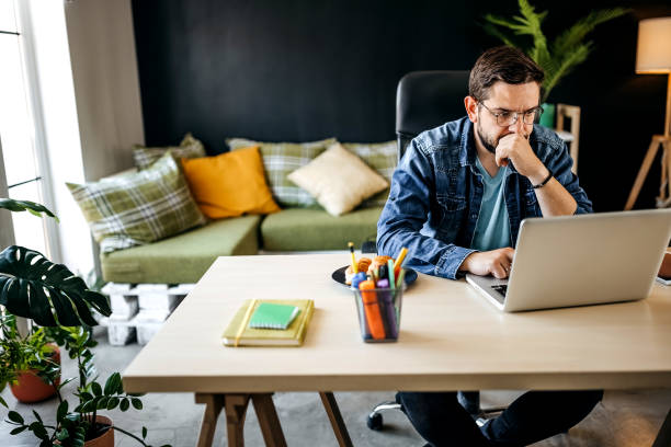 istock Cheerful male freelancer in eyeglasses sitting at work desktop while using laptop 1317795482
