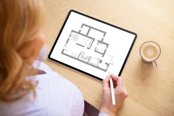 Woman working on home plan on tablet computer, above view