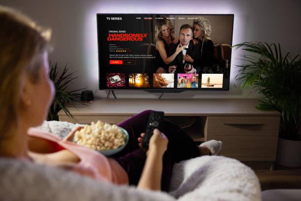 mujer viendo series de televisión y películas a través del servicio de streaming en casa - descargando fotografías e imágenes de stock
