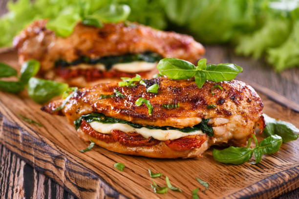 istock Baked chicken breast with mozzarella, sun-dried tomatoes, spinach. The meat is served on a wooden board with basil and lettuce. 1317800406