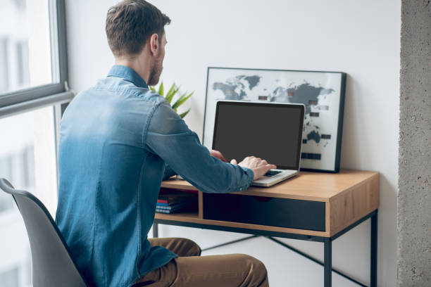 istock Dark-haired man sitting at the table and working on a laptop 1317803497