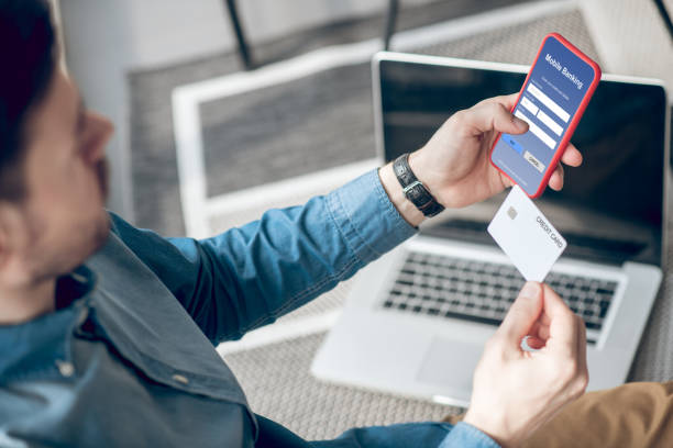 istock Man holding a smartphone and making online payment via application 1317803536