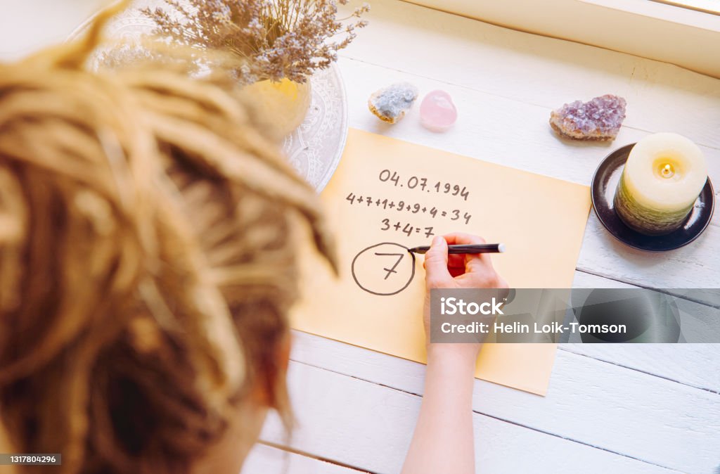 Above view of girl calculate Life path number on paper in home. Spiritual numerology concept. Numerology Stock Photo