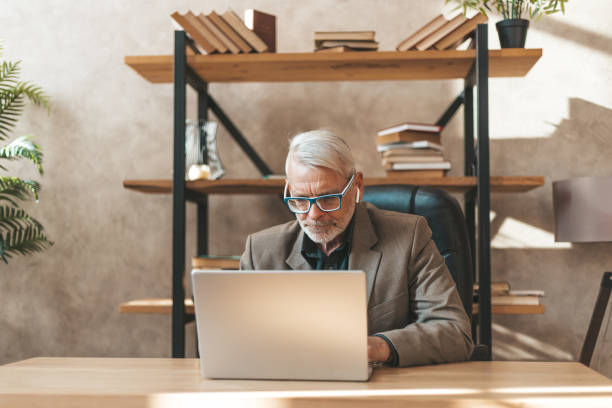 istock Focused on work. An older man with a beard works on a laptop. Internet correspondence, online services for pensioners 1317804947