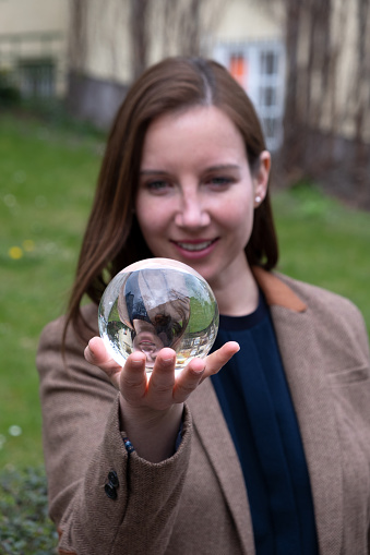 young brunette woman holding a glass sphere in her hand