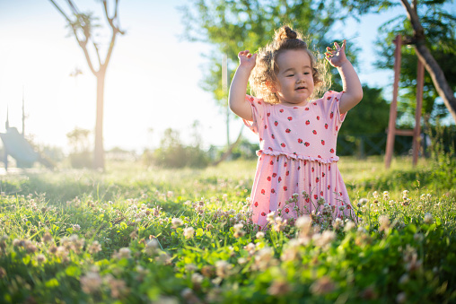 cute baby girl playing in the park lies on the grass