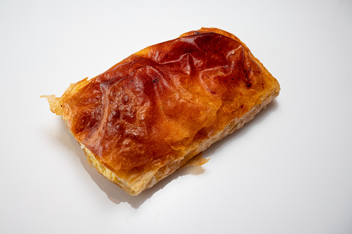 Homemade traditional pies stuffed with beef and cheese, empanadas baked and served on a white plate with green salad and salsa sauce