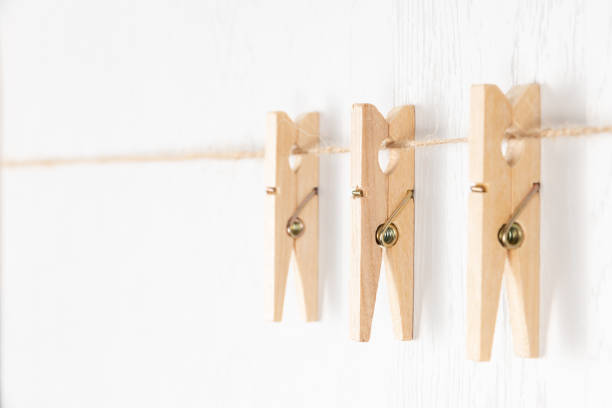 istock three wooden clothespins with a metal spring hang on a rope on a white background 1317810077