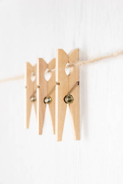 istock three wooden clothespins with a metal spring hang on a rope on a white background 1317810529