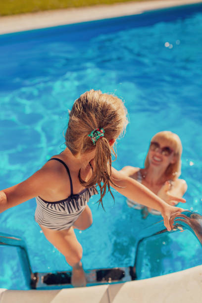 istock Mother and daughter having fun at the swimming pool 1317812864