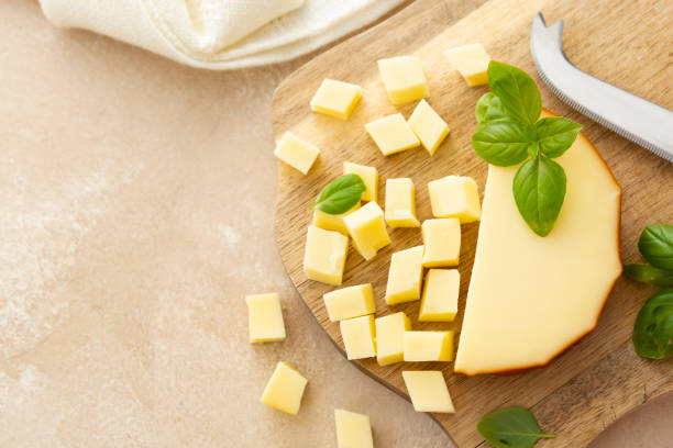 smoked cheese on cutting board with basil, sliced cheese, copy space, top view - gouda imagens e fotografias de stock