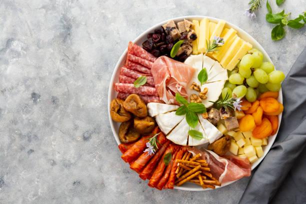 Charcuterie assortment, variety of cheeses and salami, prosciutto and dried fruits, figs, apricots, cranberries. Copy space. Charcuterie assortment, variety of cheeses and salami, prosciutto and dried fruits, figs, apricots, cranberries. Top view prosciutto brie stock pictures, royalty-free photos & images