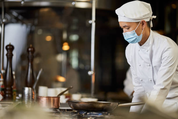 istock Focused Asian chef observing pans on the stove 1317818232