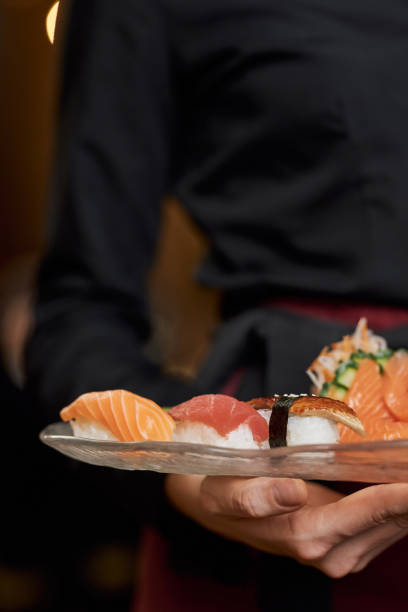 istock Appetizing sushi on plate in hands of restaurant staff 1317818257