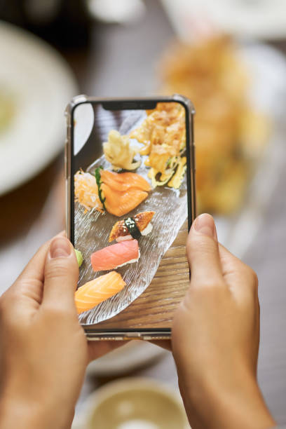 istock Person using mobile camera for photographing sushi meal 1317818289