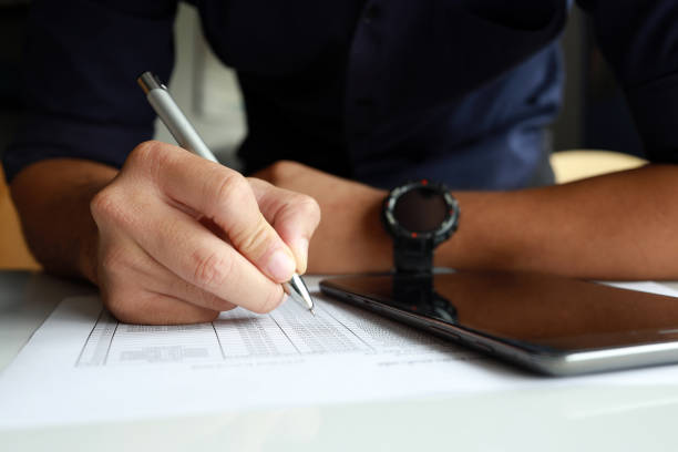 istock businessman working in the office. he is using touchpad reading an email on tablet and taking notes on the paper with soft-focus and over light in the background 1317818995