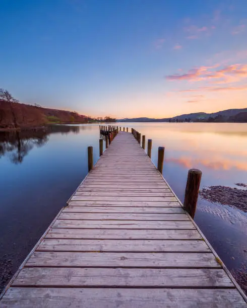 Sunset at a wooden jetty on Coniston Water in the English Lake District with a colourful sky
