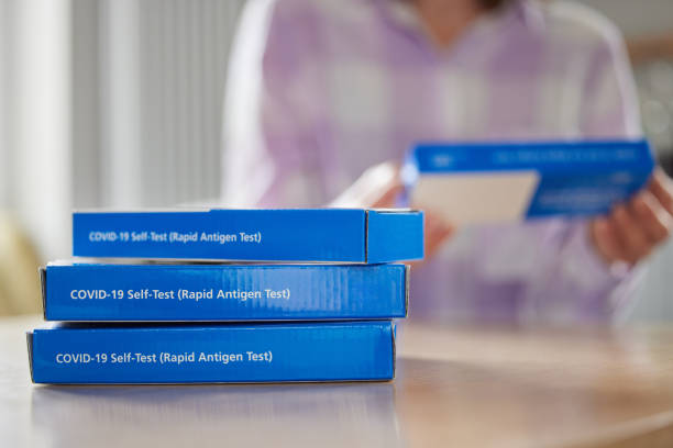 Close Up Of Woman At Home Reading Instructions On Supply Of Covid-19 Rapid Antigen Self-Testing Kits Close Up Of Woman At Home Reading Instructions On Supply Of Covid-19 Rapid Antigen Self-Testing Kits pcr device photos stock pictures, royalty-free photos & images