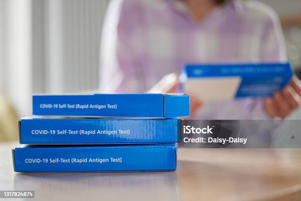 Close Up Of Woman At Home Reading Instructions On Supply Of Covid19 Rapid Antigen Selftesting Kits Stock Photo - Download Image Now