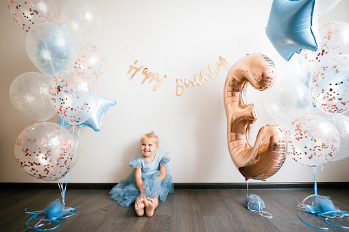 Birthday of a little blonde girl. Child in festive balloons. High quality photo